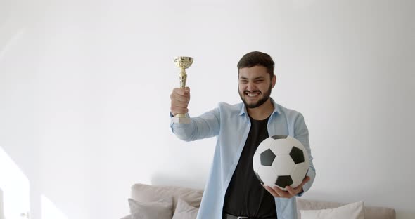 A Young Indian Football Fan is Watching TV at Home