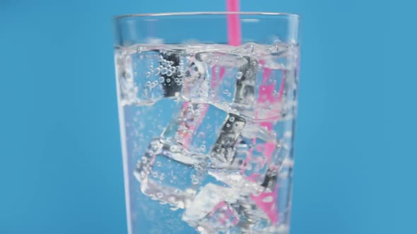 Somebody Mix Cold Water Drink with Pink Drinking Straw Glass Full of Fizzy with Ice Cubes