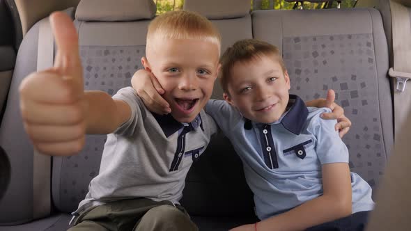 Portrait of Two Little Boys in the Back Seat of a Car They Give a Thumbs Up