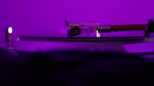 A Vintage Record Player Needle spins a warped and distorted record under a black light while a Disk