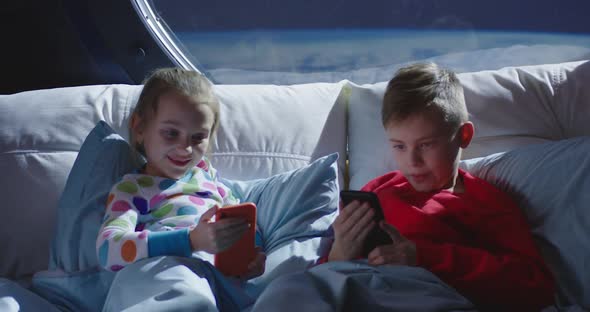 Boy and Girl Using Cell Phones in Bed