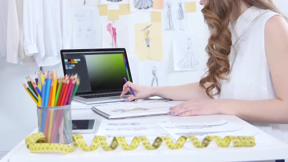 Girl Draws the Outline of the Collection, on the Table Lie Old Sketches and Colored Pencils