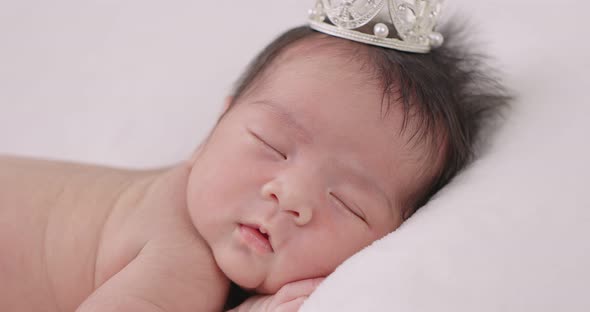 Slow Motion Shot Of Cute Newborn Baby Sleeps Wearing A Gold Crown.