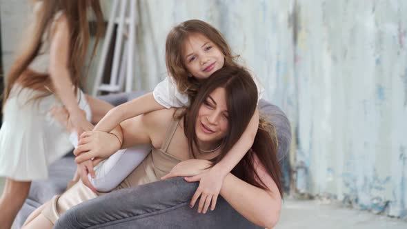 Mom Lies on the Couch and Cuddles with Her Daughters