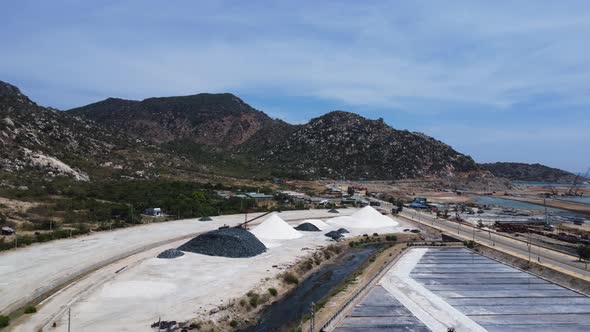 Aerial over vast salt fields spread amidst mountains in Phan Rang, Vietnam.