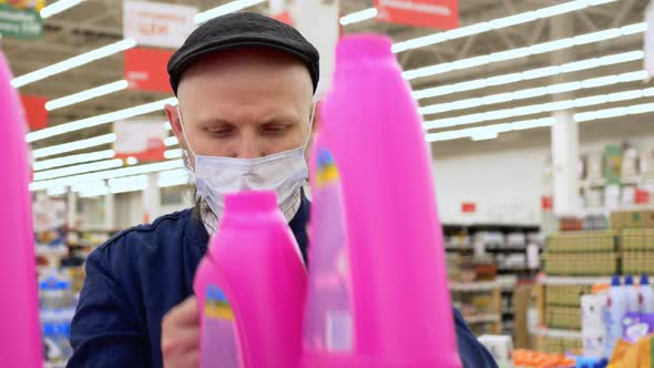 A Man in a Mask Against Coronavirus is Bought in a Store with Cleaning Products Washing Powder for