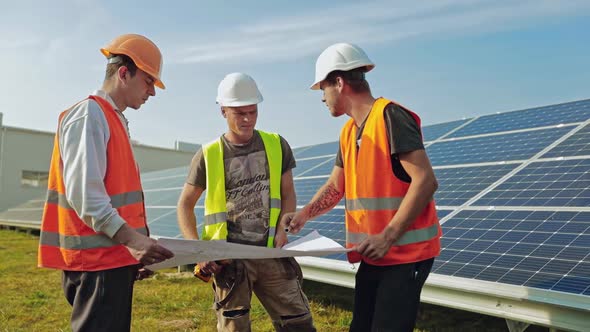 Engineers work at solar panel plant. Young engineers checking project of solar plant