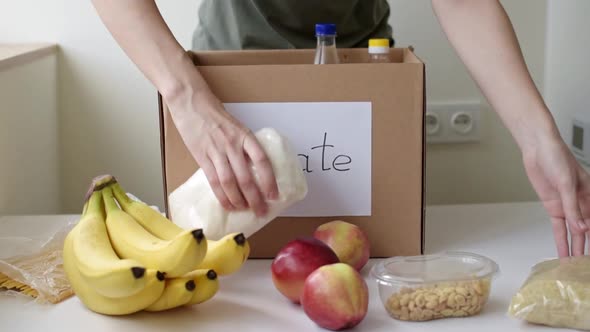 Woman Glues Sheet with Inscription Donate on the Box with Products
