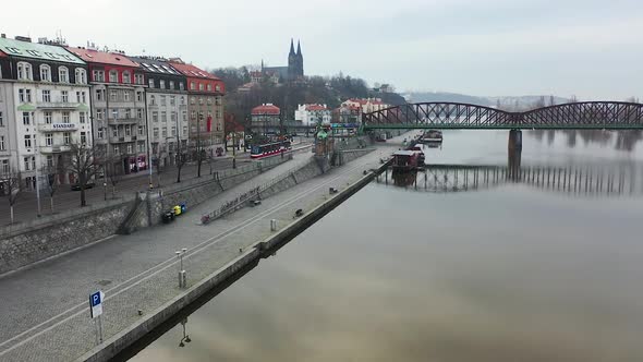 Aerial View of Naplavka Riverwalk, Prague, Czech Republic. Railway Bridge, City Traffic on Misty Aut