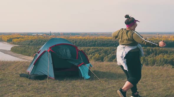 Tipsy Girls Hug on Meadow at Tent Against Autumn Forests