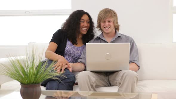 Couple sitting on couch with laptop computer