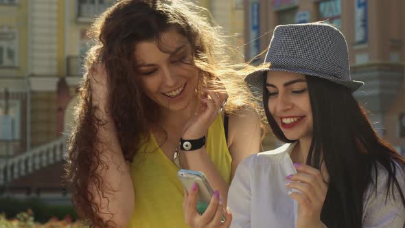 Two Girls Discuss Something on Smartphone