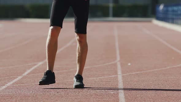 Sportsman Warming Up Leg Muscles at Stadium for Better Blood Circulation