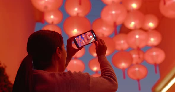 Woman take photo on cellphone under red lantern at night