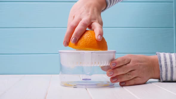 girl makes orange juice through a juicer. close-up