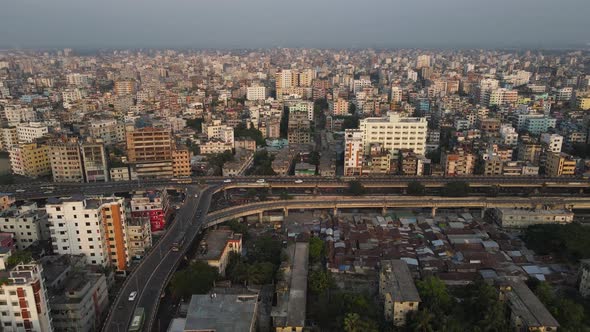 Aerial drone shot of Dhaka showing flyover and traffic with densely populated city buildings.