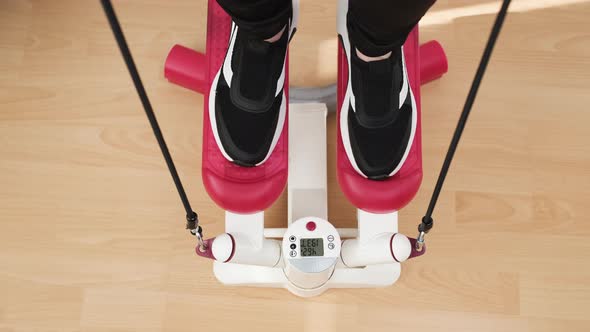 View Above on the Woman Feet Doing Exercises on the Red Twist Stepper in the Black Sneakers at Home