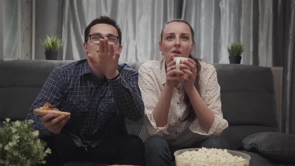 Young Friends Man and Woman Emotionally Watching Football Game on TV Together at Home. alt