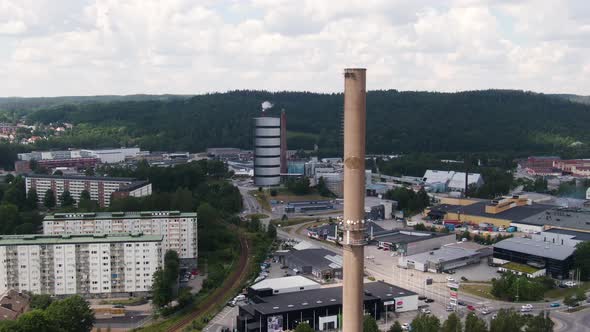 Apartment buildings and massive industrial chimney in Swedish city, aerial drone view