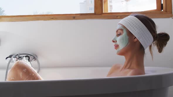 Woman wearing face pack relaxing in bathtub