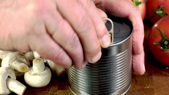 Hand Opens Metallic Tin Can of Marinated Green Pea