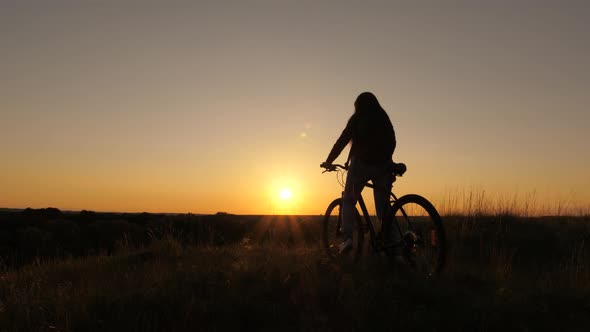 Free Girl Travels with a Bicycle at Sunset. Concept of Adventure and Travel. Hiker Healthy Young