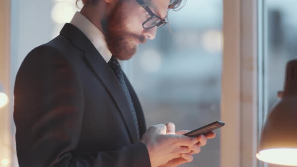 View through Glass Wall of Businessman Typing on Phone and Answering Call