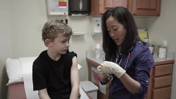 Doctor giving a shot to a young boy.