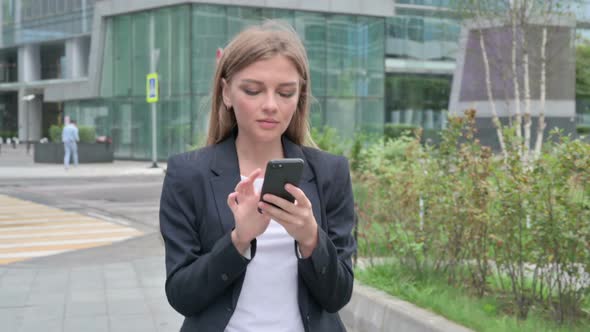 Businesswoman Using Smartphone While Walking on the Street