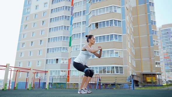 Slender woman in the yard of the house is engaged with fitness rubber