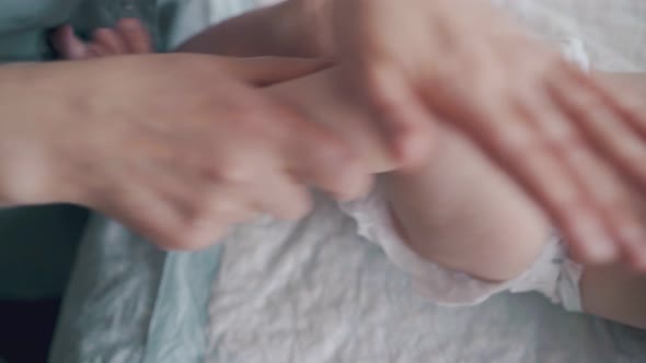 Nurse Massages Flexes and Stretches Lying in Bed Infant Legs