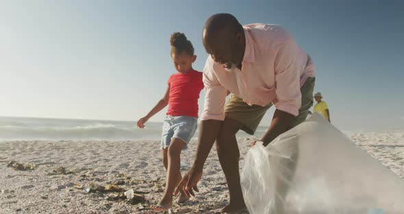 Senior african american couple with grandchildren segregating waste on sunny beach