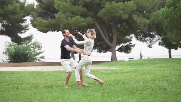 A Woman Runs into the Arms of a Man at a Park in the Rain, Slow Motion
