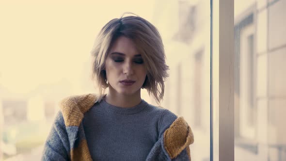 CU Portrait of Young Girl with a Mysterious Look Against the Background of Windows