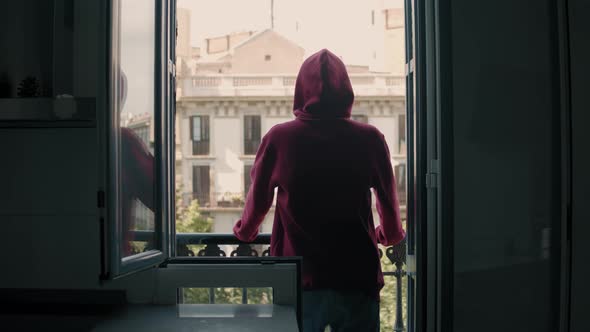 Isolated and Depressed Millennial Teen Man Watching the Empty Streets From His Balcony in Sadness