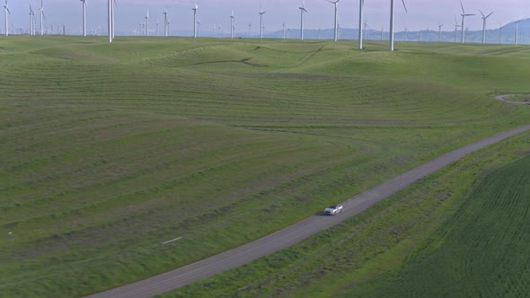 Car Driving On The Dirt Road Among Windmills