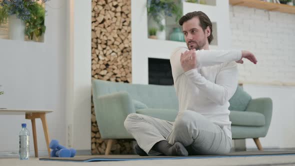 Young Man Doing Stretches on Yoga Mat at Home