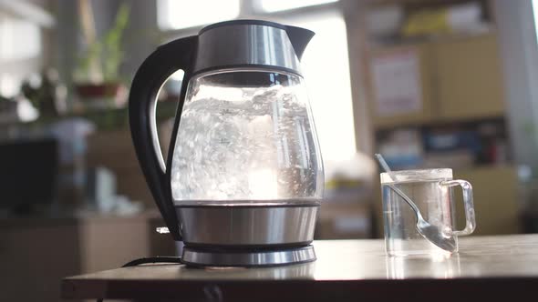 Slider Shot of a Transparent Kettle with Water Boils