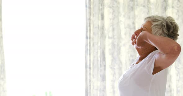 Senior woman waking up and stretching in bed