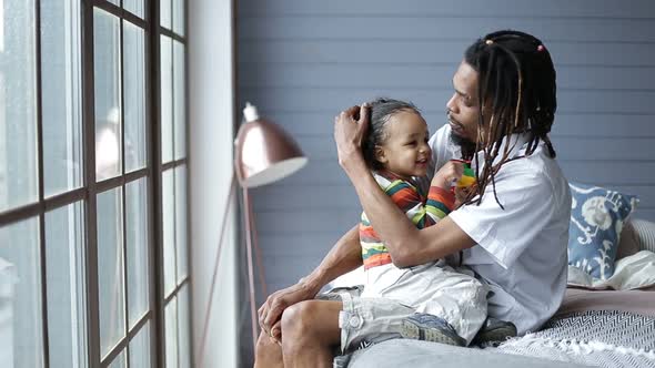 Mixed Race Boy Sitting on Father's Lap at Home