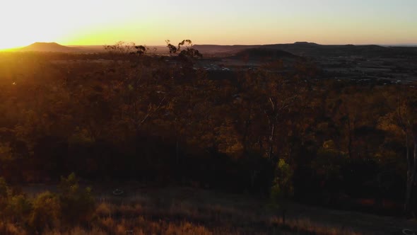 The camera flies past a man bathed in the warm sunset glow and flies into the valley