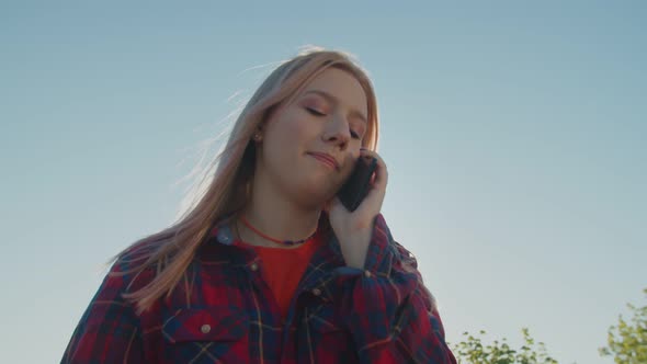 Cute Hipster Female Walking and Chatting on Smartphone at Daybreak