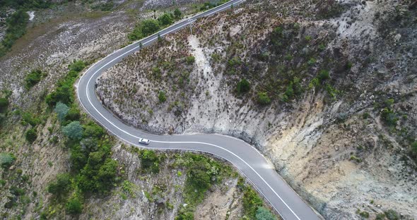 Aerial shot of a car driving on a windy road in Tasmania, Australia. Shot is looking down at the veh