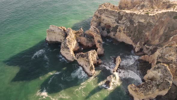 Limestone cliffs that form the coastline Lagos, Algarve. Waves washing on rocks. Orbiting shot