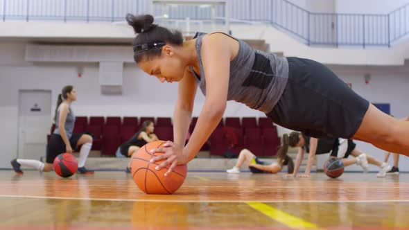 African Girl Doing Pushups with Basketball on Court and Laughing