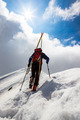 Ski mountaineer walking up along a steep snowy ridge with the skis in the backpack. - PhotoDune Item for Sale