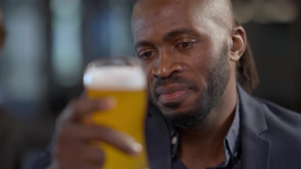 Headshot Portrait of Satisfied African American Man Holding Pale Lager Smiling