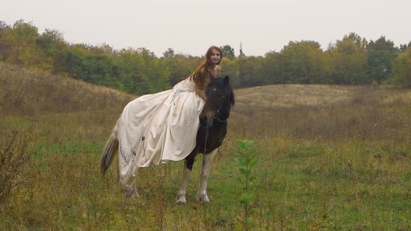 Red-haired Horsewoman in Poofy Dress Is Riding Horse on Field