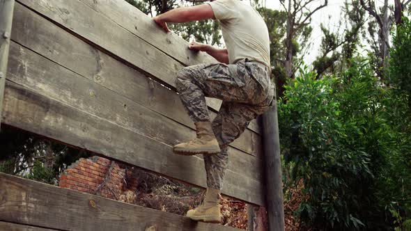 Military soldier climbing a wooden wall at boot camp 4k