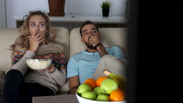 Revealing Shot of Couple on the Couch in the Living Room Watching a Scary Horror Movie
